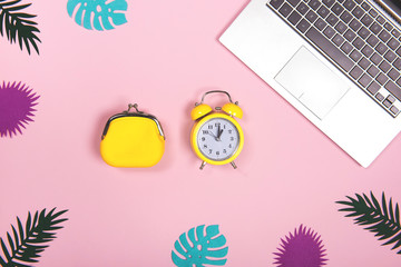 Office workplace with laptop computer and alarm clock, with tropical decoration. Business holidays flat lay concept.