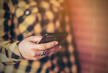 Smart Casual Business Woman ware yellow shirt gingham, doing or touching text message on smart phone or technology. hipster Girls using Mobile phone on old brick wall background.