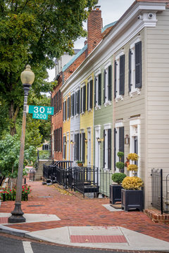 View of colonial row house, townhome, with colorful, yellow, blue, green vinyl siding on a quiet street in Georgetown Washington DC USA