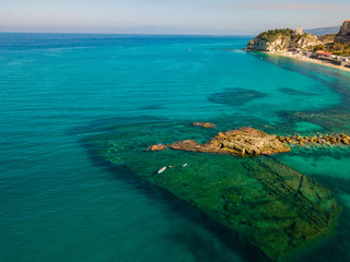 Aerial view of a beach with umbrellas and bathers. Promontory of the Sanctuary of Santa Maria dell'Isola, Tropea, Calabria, Italy.