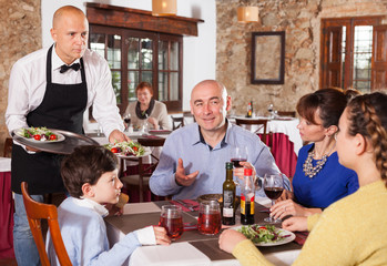 Fototapeta na wymiar Waiter serving dishes to family