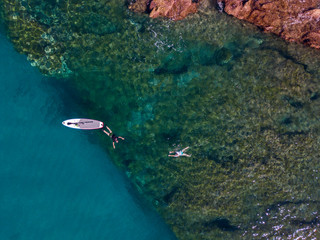 Aerial view of a paddle board in the water floating on a transparent sea, snorkeling. Bathers at...