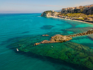 Aerial view of a beach with umbrellas and bathers. Promontory of the Sanctuary of Santa Maria dell'Isola, Tropea, Calabria, Italy.
