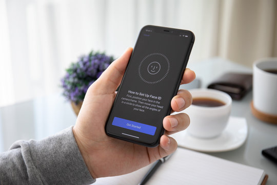 Man hand holding iPhone 11 with scanning Face ID