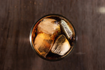 Cola and ice in a clear glass on wood table