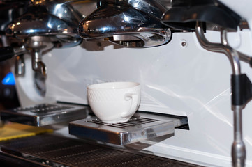 white cup in coffe machine pouring in cafe