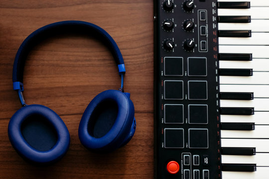 Closeup recording electronic music track with portable midi keyboard and headphones in home studio. Producing and mixing music, beat making and arranging audio content with professional audio devices