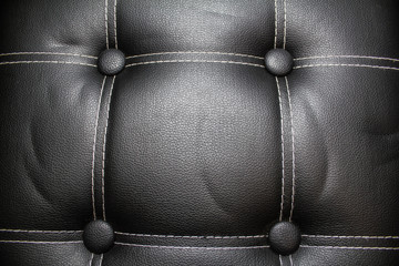 Texture of a black leather armchair with a white seam