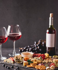Red wine with different kinds of cheese, charcuterie assortment, crackers, grapes, nuts and berries