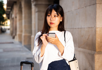 Young chinese female is looking up the way in phone by using gps