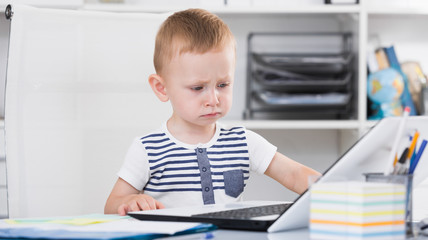 Young cute child is watching cartoons on laptop