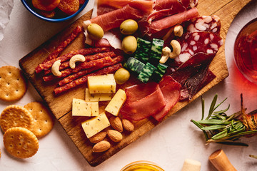 Red wine with different kinds of cheese, charcuterie assortment, crackers, grapes, nuts