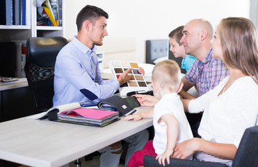 Obraz premium Handsome salesman in furniture store helping young family in choice