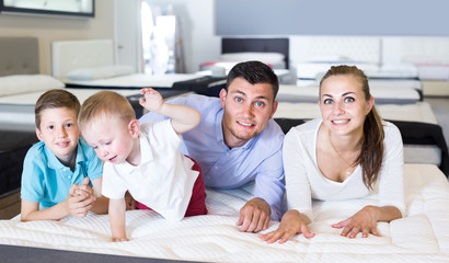  parents with two young sons testing mattress in store