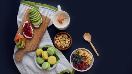 breakfast top view black background. oatmeal with berries, toasts on a wooden tray, nuts, coffee