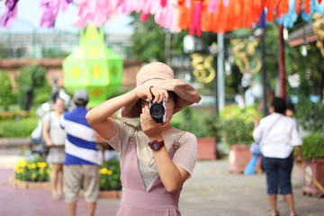 A woman with a camera stands to take pictures of people around her.​ color​ful​ background.