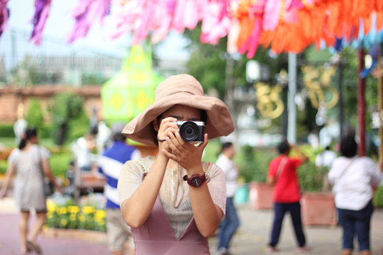 A woman with a camera stands to take pictures of people around her.​ color​ful​ background.