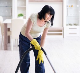 Senior old woman tired after vacuum cleaning house