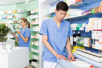 Man pharmacist is searching medicines on shelves