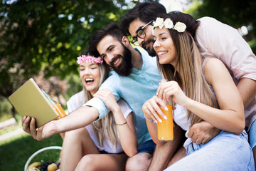 Fototapeta premium Happy friends in the park having picnic on a sunny day.