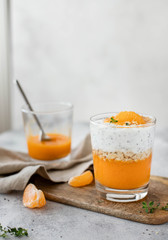healthy chia pudding with mandarin and persimmon. Autumn or winter dessert. light gray background.