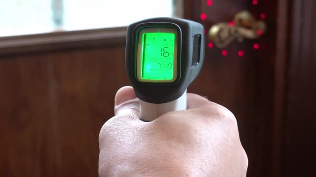 Measuring temperature with infrared laser thermometer. Checking heat leakage from door.