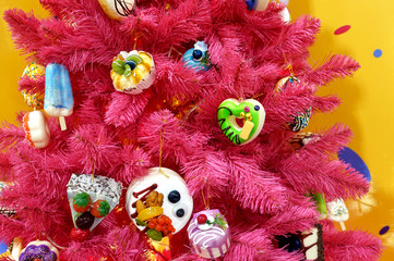 Red christmas tree decorated with sweets toys. Bright gingerbread cookies, ice cream and candy on a Christmas tree.  