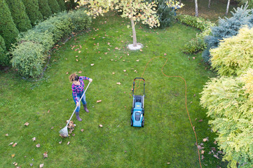 Woman raking leaves and trimming lawn