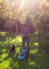 Woman and dog mowing lawn in garden