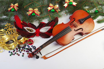 Violin, carnival masks, branches of spruce and New Year decorations.