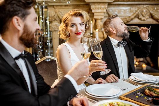 Elegantly dressed people having a festive dinner indoors