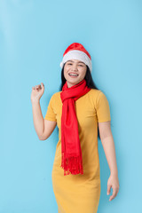 Asian woman in yellow dress wearing red scarf and Santa hat, holidays concept.