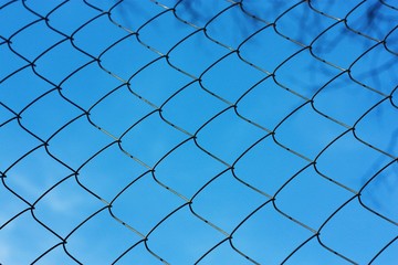 Fototapeta premium Black metal mesh on the background and blue sky 