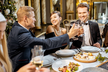 Elegantly dressed people celebrating New Year holiday indoors