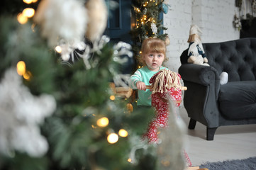 Little cute girl child sitting on a red rocking horse on a background of Christmas interior