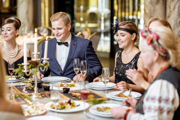Elegantly dressed people having a festive dinner indoors