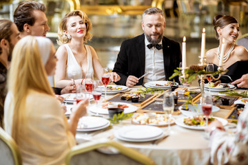 Elegantly dressed people having a festive dinner indoors