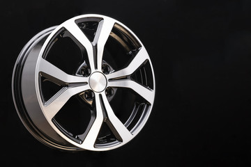 Obraz premium new cast aluminum wheel disc close up on black background. forked spokes, black and polished surface, copyspace,
