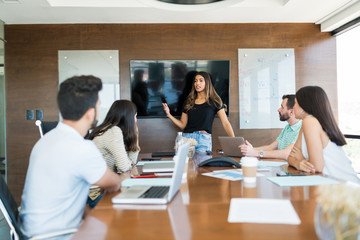 Businesswoman Sharing Ideas With Team In Office Meeting