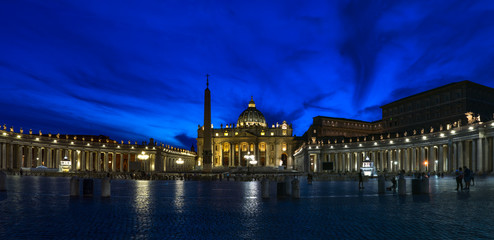 Night panorama of Vatican city. Bernini's colonnade, Maderno's fountain and St. Peter's Basilica at night during blue hour.
