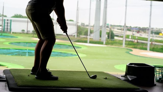 Close-up of golf ball on tee with golf club overlooking driving range at Topgolf