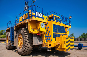 Heavy yellow quarry tractor at repair station at sunny cloudless day