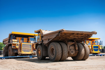 Obraz premium heavy yellow quarry dump truck at repair station at sunny cloudless day