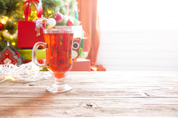 One glass cup of christmas mulled wine or gluhwein with spices and orange slices on rustic wooden table top view
