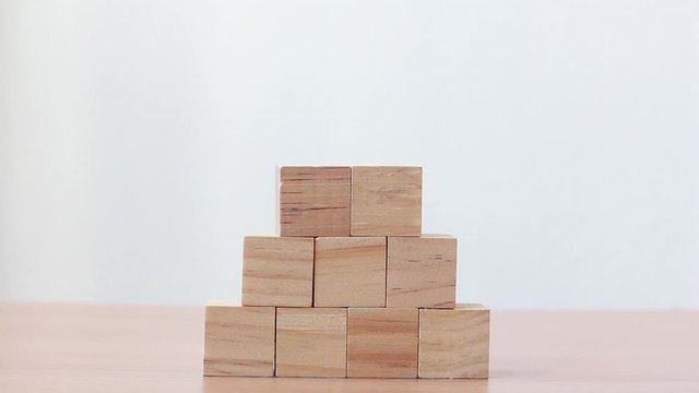 Hand putting wood cube on top of wood block stacking as step stair.business growth to success.