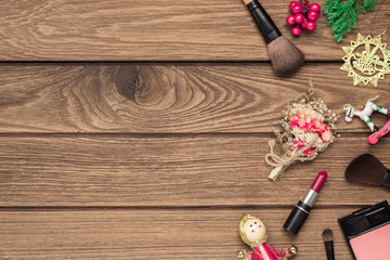 Woman cosmetics, makeup brushes, lipstick and Christmas ornaments on wood background, Flat lay top view with copy space. Christmas time and New year cosmetics background concept.