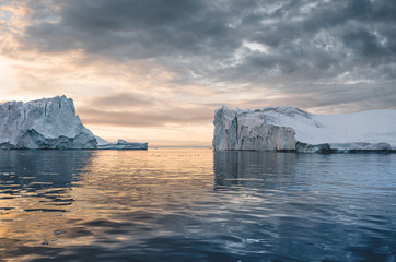 Arctic nature landscape with icebergs in Greenland icefjord with midnight sun sunset sunrise in the...