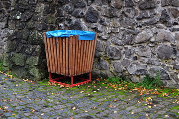 Alter Müllleimer aus Holz mit blauem Müllsack im Innenhof der alten Burgruine aus Bruchstein und...