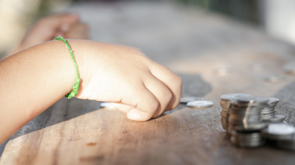 The boy hand holding money coin and stack with layered coin is much more. Business and Finance concept. Money saving concept.