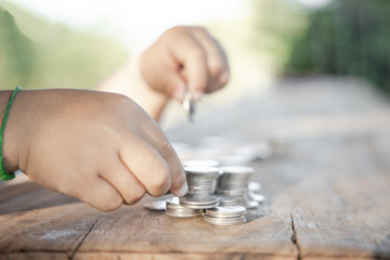 The boy hand holding money coin and stack with layered coin is much more. Business and Finance concept. Money saving concept.